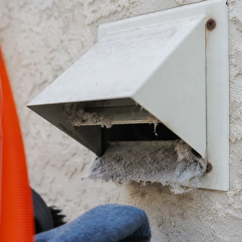 Exterior dryer vent hood with a damper flap partially stuck by lint